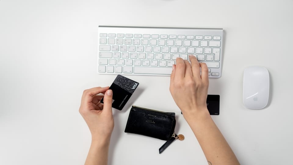person-holding-credit-card-using-keyboard
